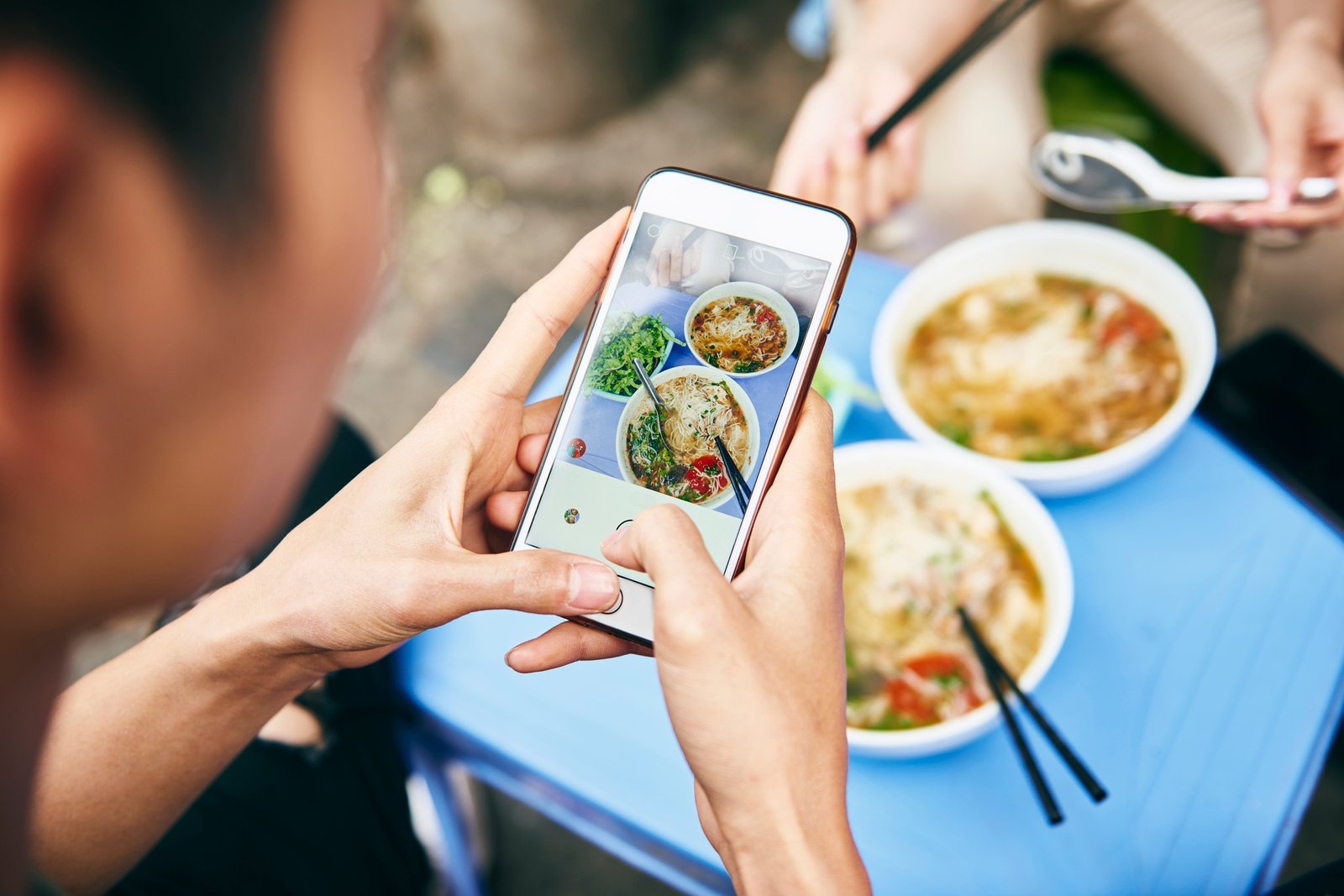 Close up of man photographing his Vietnamese food